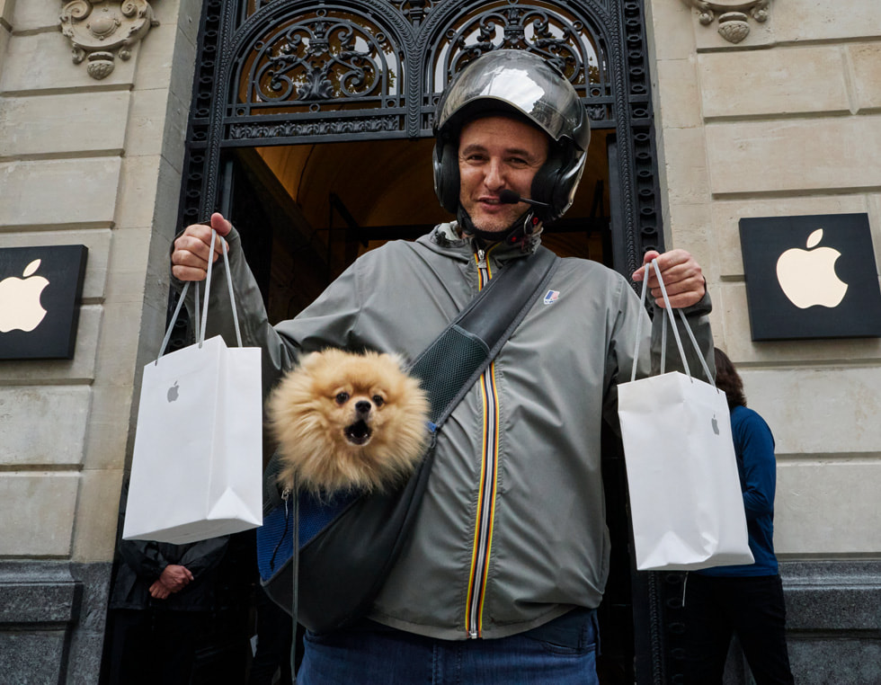 A customer examines a display model from the iPhone 14 lineup at Apple Champs-Élysées.