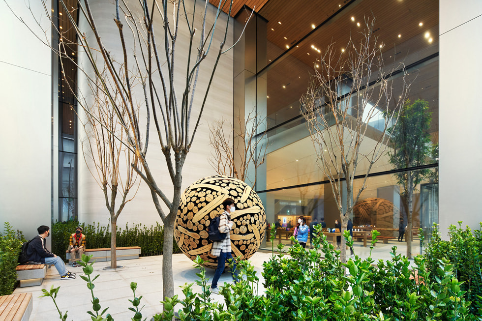 Apple 명동 외부에 마련된 작은 정원을 거니는 고객의 모습.