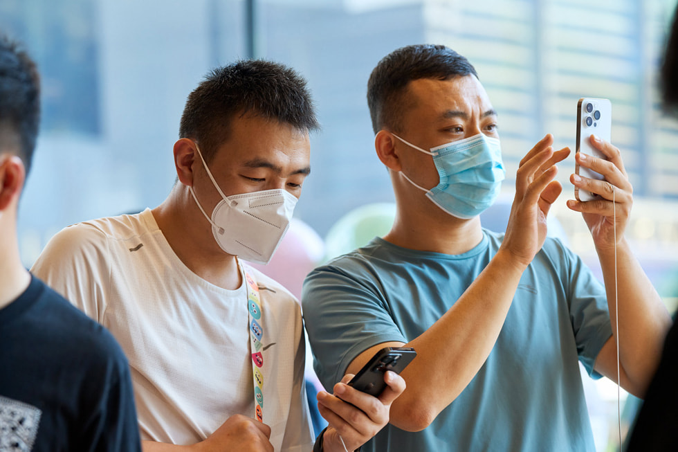 Two Apple Sanlitun customers each testing iPhone 14 Pro.