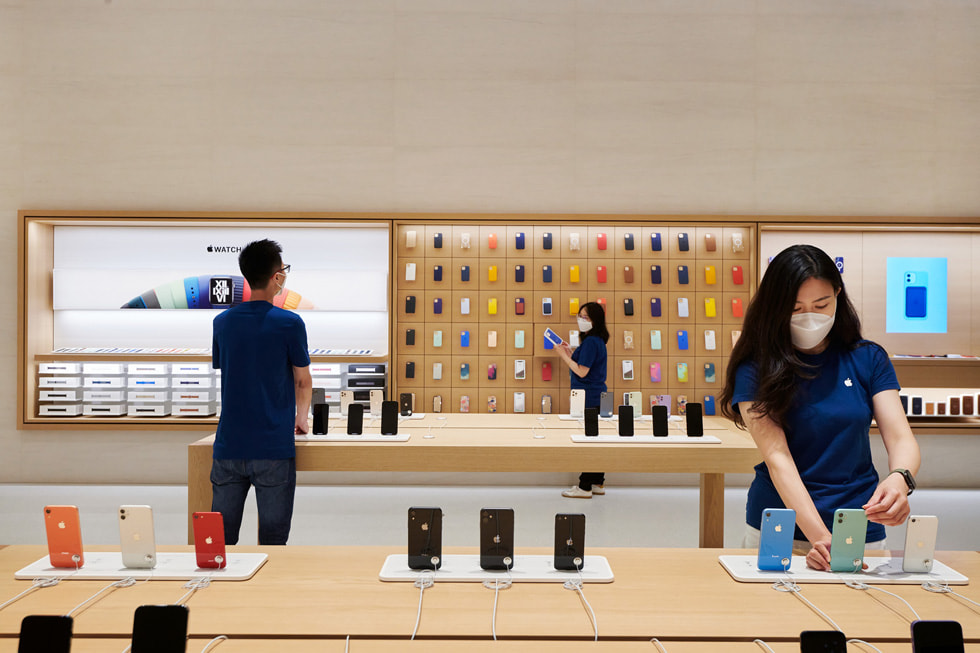 Retail team members setting up iPhone devices on display tables inside Apple Changsha.