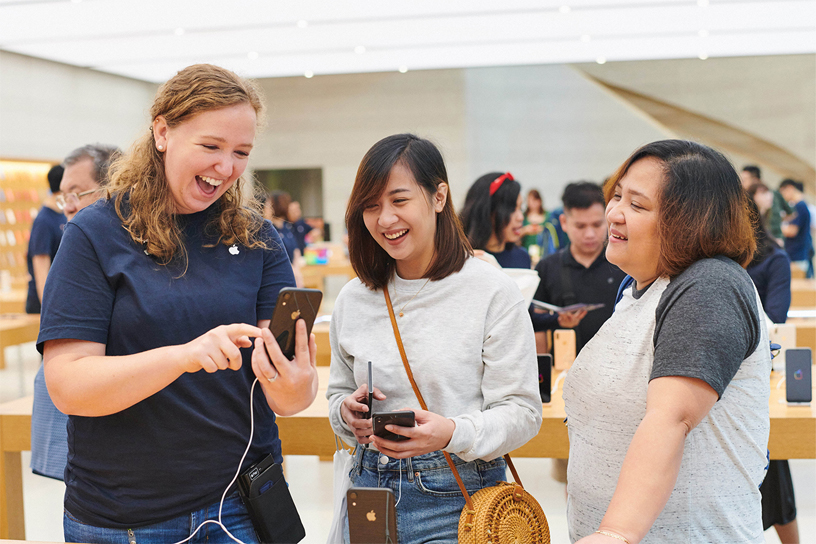 Apple team member shows iPhone XR to two customers.