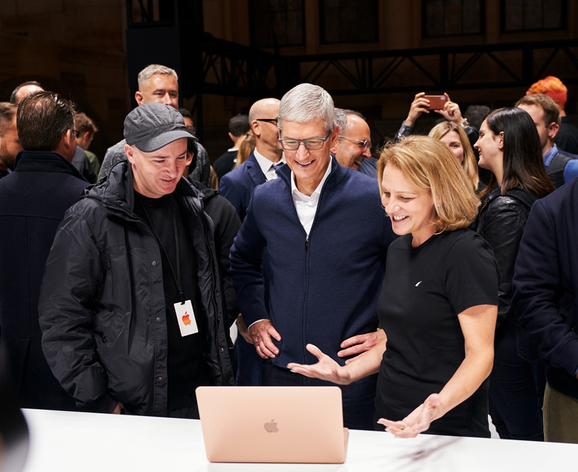 KAWS and Tim Cook check out the MacBook Air with an Apple team member.