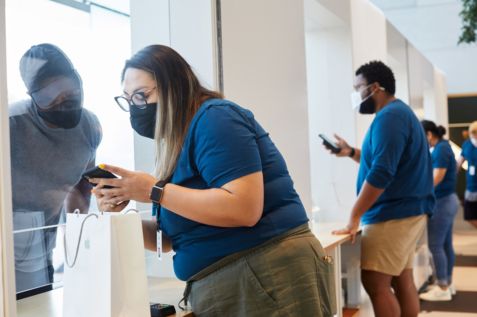 An Apple employee helps a customer with his Apple purchase at Apple Highland Village.
