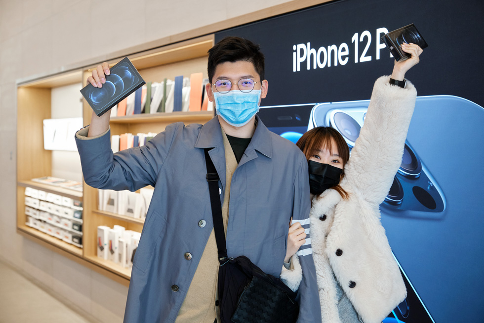 Customers at Apple Sanlitun show off their new iPhone 12 Pro Max purchases.