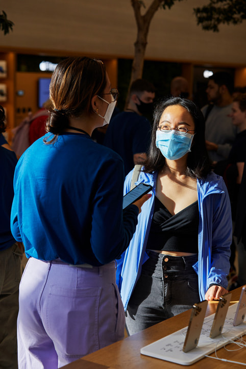 An Apple Regent Street team member advises a customer on the new iPhone 13 models.