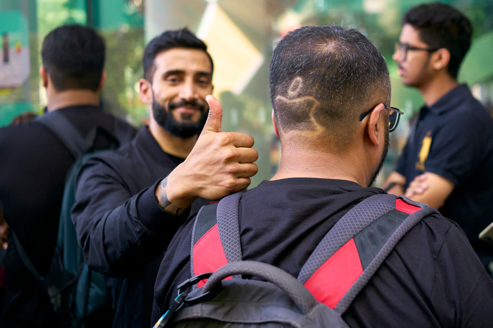 A customer shows off his haircut, including an Apple logo traced into his hair.