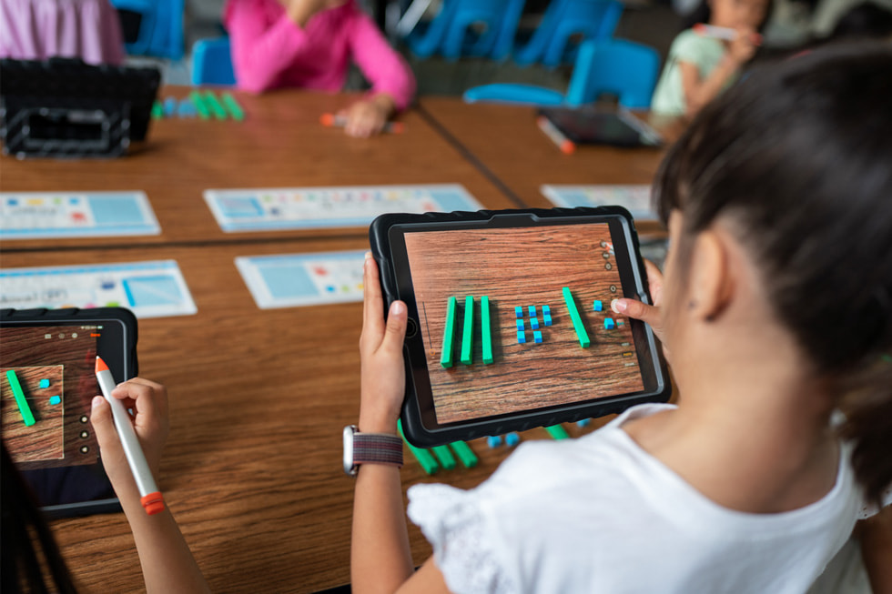 A student is shown using iPad in a classroom setting.