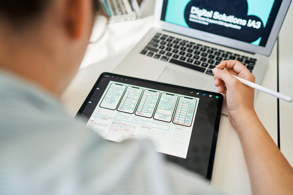 Using iPad, Apple Pencil, and MacBook Air, a student works on developing an app.