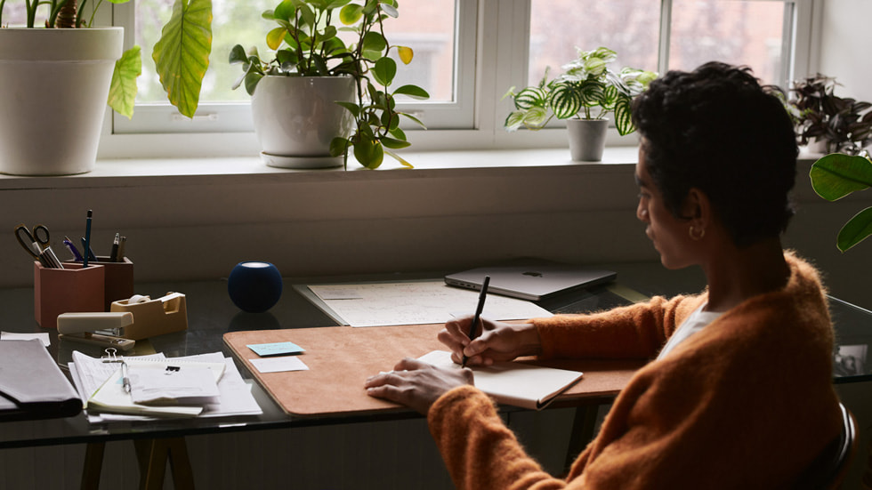 Man working on his desk with HomePod mini in blue.