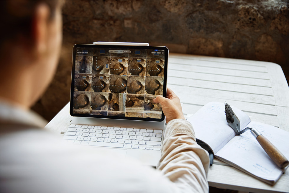 Shot from over the shoulder, an archaeologist reviews excavation images on iPad Pro.