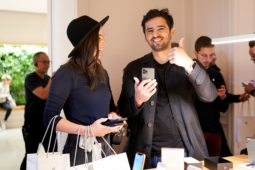 An Apple team member helps a customer holding an iPhone 11 Pro at Apple Champs-Élysées.