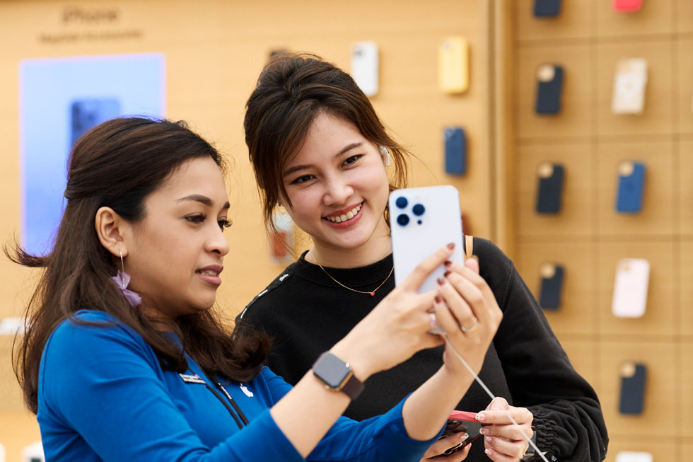 An Apple Orchard Road team member showing a woman iPhone 14 Pro in silver.