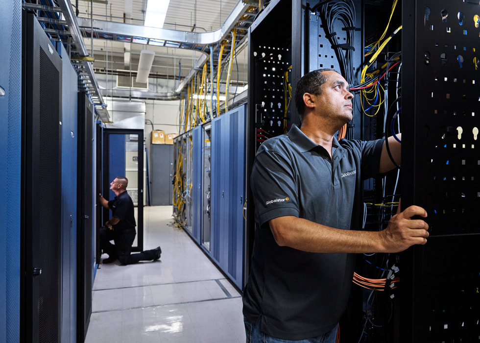 Two satellite technicians are shown working in a hallway.