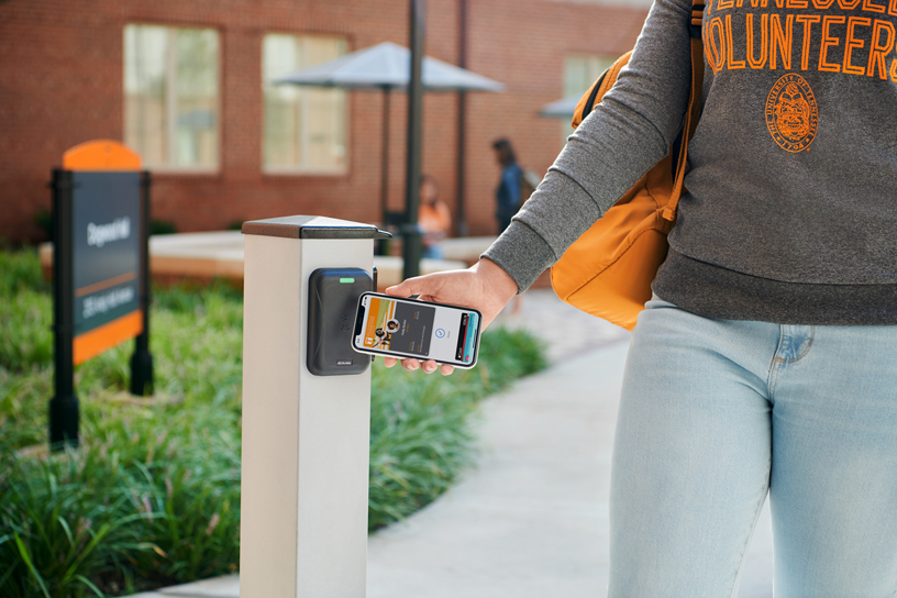 A student uses a contactless student ID on iPhone to enter a campus building.