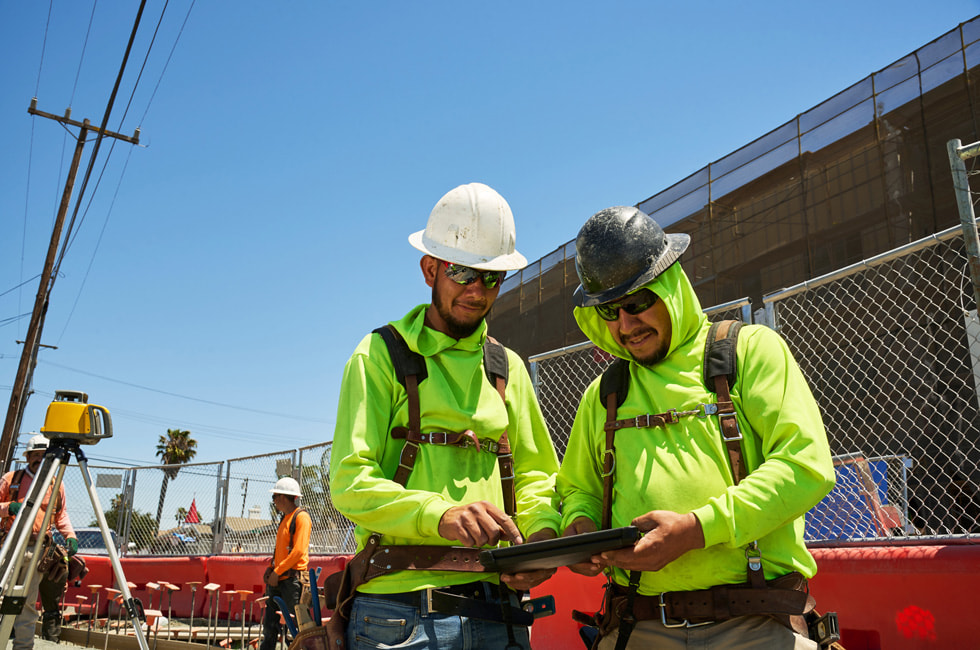 Two workers on a construction site using iPad