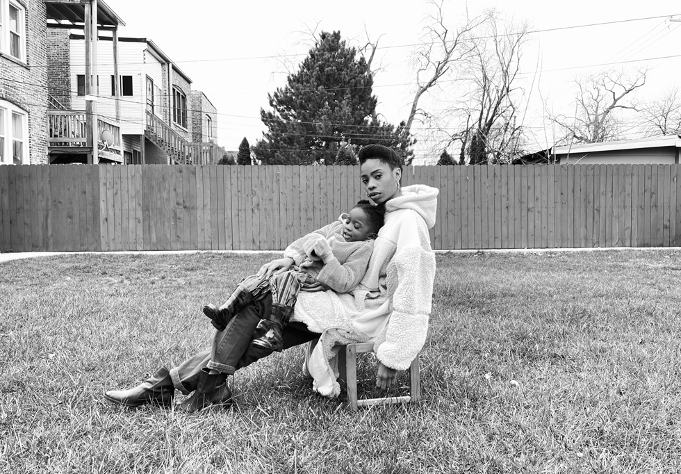 A woman with a child in her lap, seated outdoors.