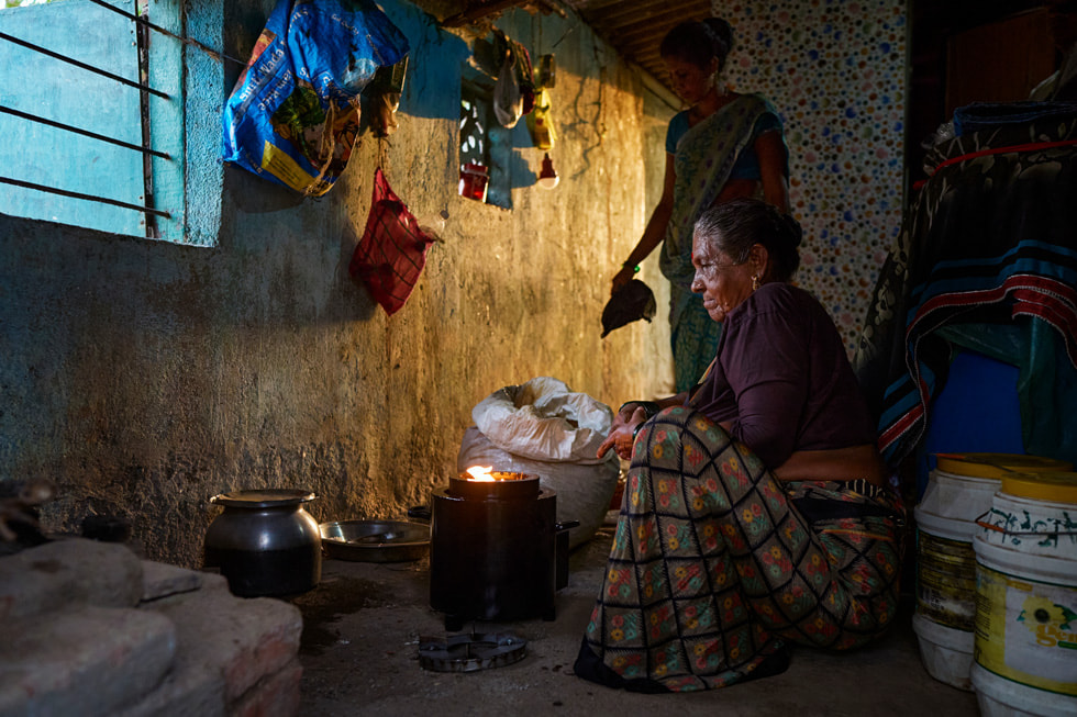 Two Indian women cook using a portable bio-stove.
