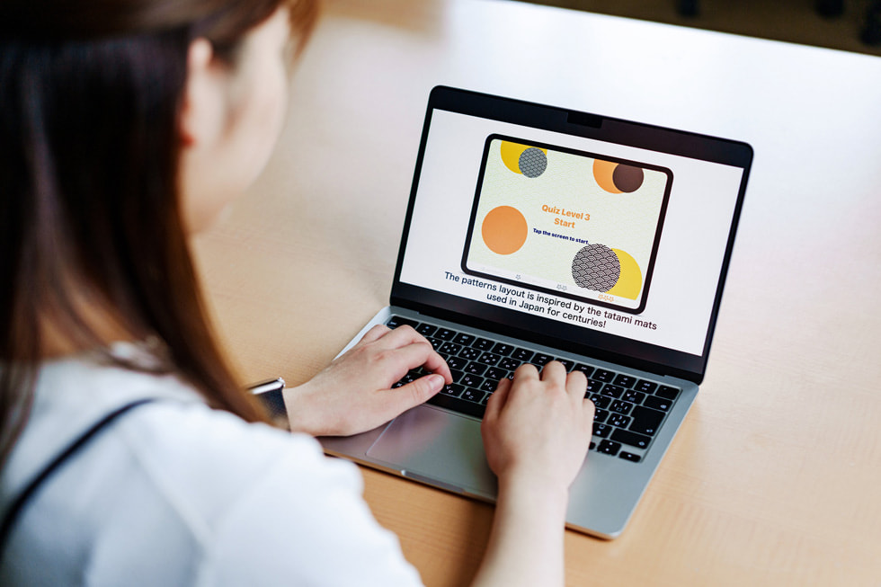 MacBookでSwiftプログラミング言語を学ぶ学生を肩ごしに撮影した写真。