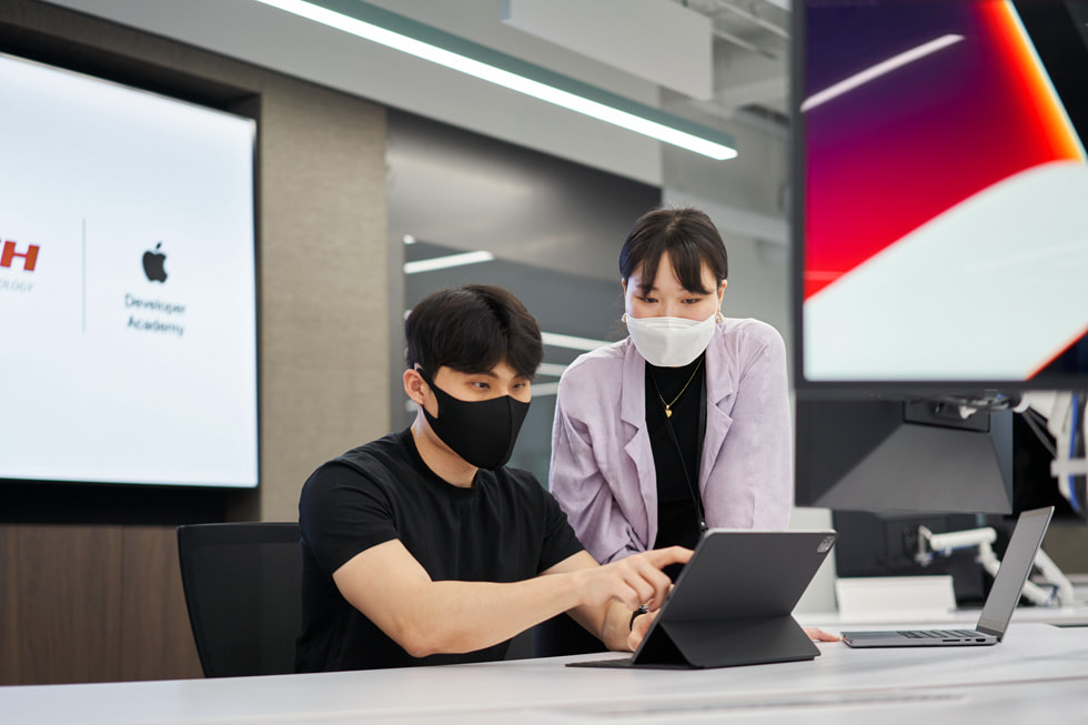 대한민국 포항시에 개소한 Apple Developer Academy에서 학생의 수업 화면을 바라보고 있는 교육진의 모습.