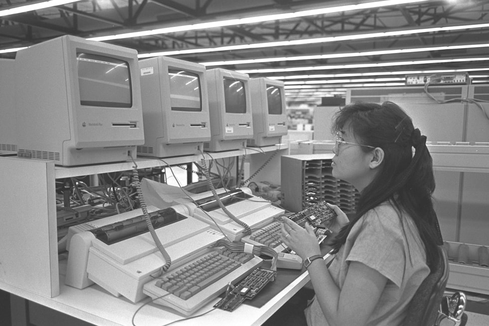An Apple facility worker inspects machines from the Apple II series.