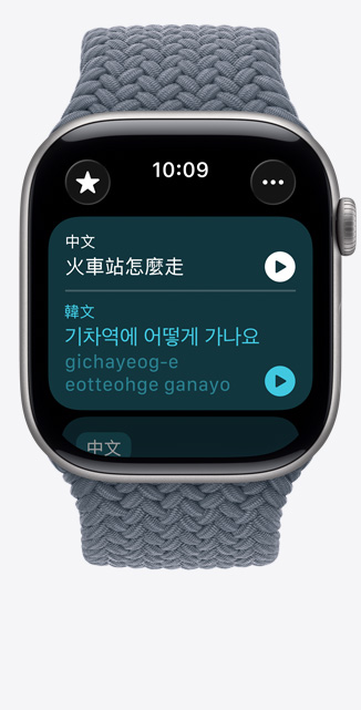 Apple Watch Series 11，展示太空灰色鋁金屬錶殼，搭配錨藍色編織單圈錶環，螢幕上的翻譯 app 顯示要怎麼去火車站的韓文翻譯和發音