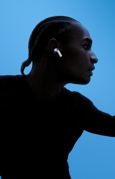 A person wearing AirPods 5, arms spread, colored background