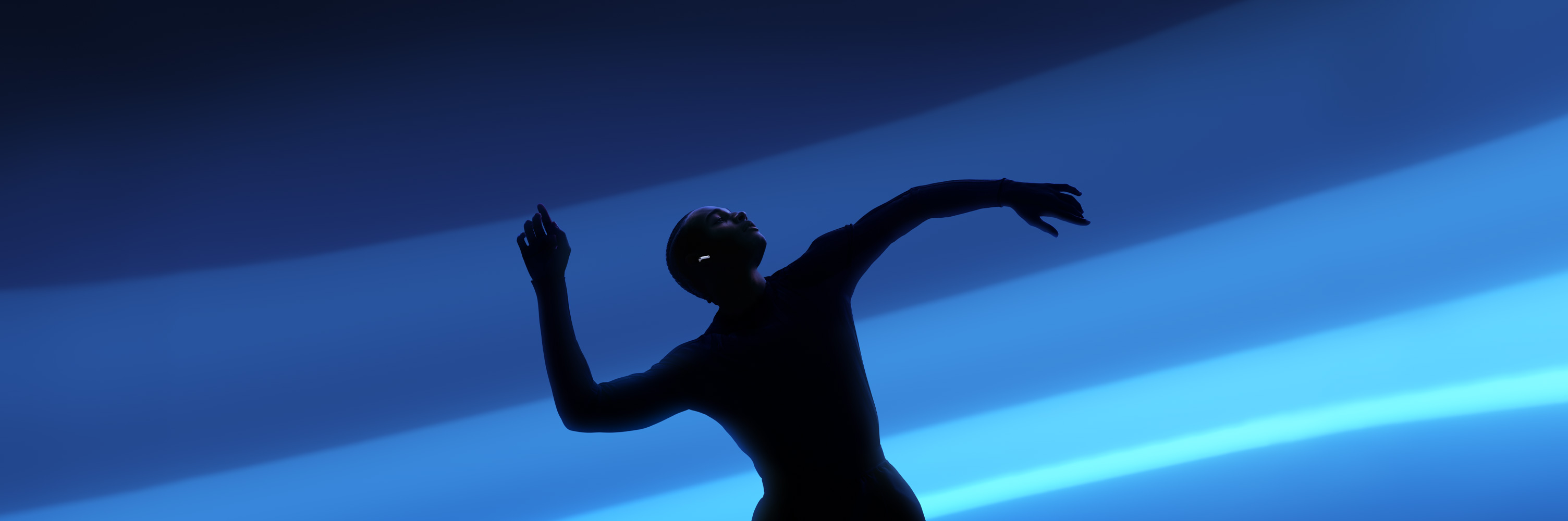 A person wearing AirPods 5 as they move with their arms spread wide