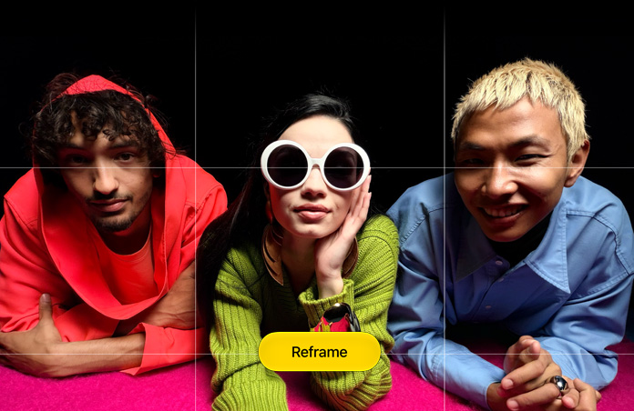 Brightly hued close-up photo of three people leaning forward over a pink surface, a grid appears over it, along with a button that reads: Reframe