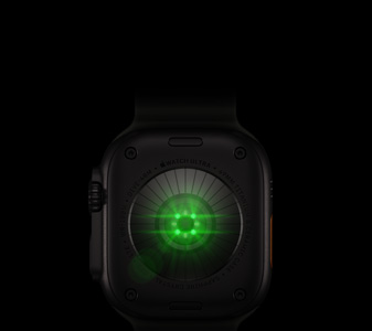 Back of Apple Watch Ultra 4, titanium case, black color, multiple round sensors with glowing green LED lights, left side exterior, Digital Crown, raised side button
