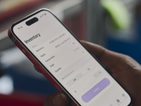 Una mano sujeta un iPhone en primer plano. En la pantalla se muestra el seguimiento del inventario.