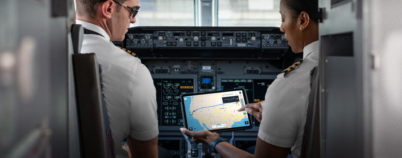 Dos pilotos en una cabina miran un mapa en la pantalla de un iPad.