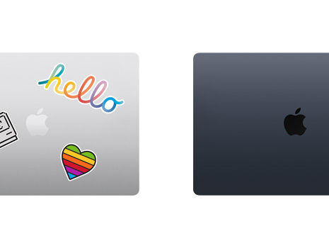 A top down view of two closed Mac laptops, one with stickers.