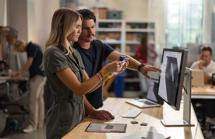 兩名學生在 Mac Studio Display 上檢視 3D 專案，同時使用真實的組件模型進行協作，而 MacBook、Apple Pencil 和 iPad 則放在桌上