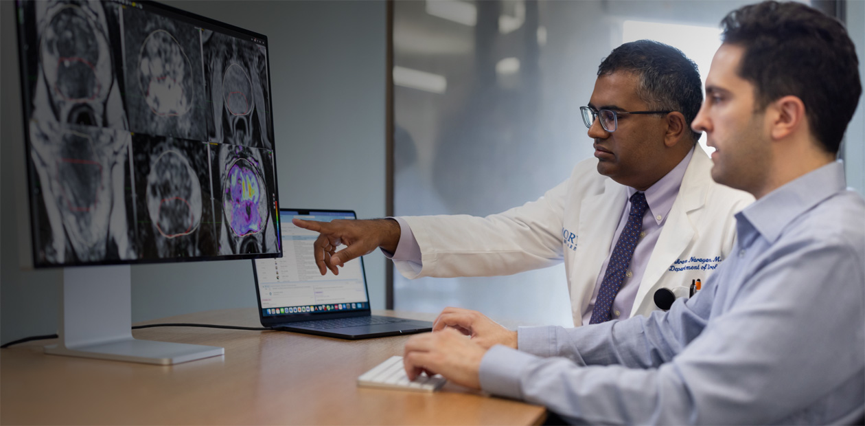 Two physicians looking at radiology images on an iMac.