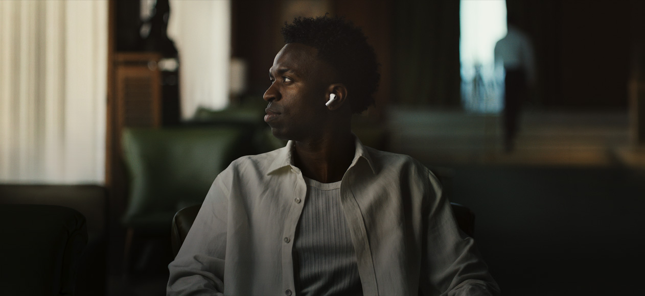 Una persona con una camisa blanca, cabeza girada hacia un lado, se ve el auricular izquierdo de unos AirPods Pro 3