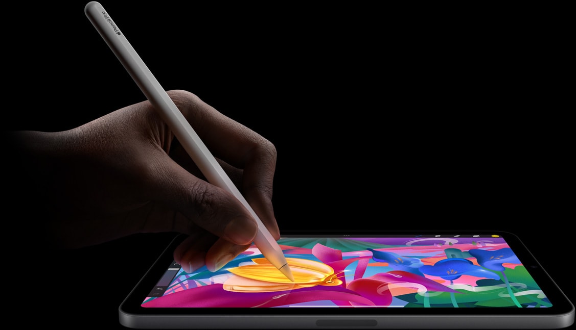 Mão com o Apple Pencil Pro a criar trabalhos artísticos coloridos no iPad mini.