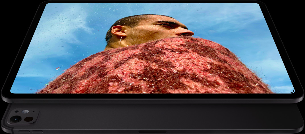 iPad Pro, Vorderansicht, Querformat, Farbe Space Schwarz, gerundete Ecken, schwarzer Displayrand, das Display zeigt das Foto eines Mannes in einem roten Pullover unter einem blauen Himmel, darunter ist ein weiteres iPad Pro, Rückansicht, Querformat, Farbe Space Schwarz, Pro Kamera-System, Lautstärketasten