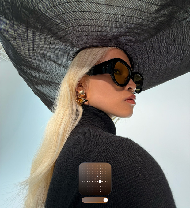 Et portrætfoto af en kvinde med en bredskygget sort hat. Billedet demonstrerer fotostilen Lys, som gør billeder optaget i svagt lys og Nat-tilstand lysere