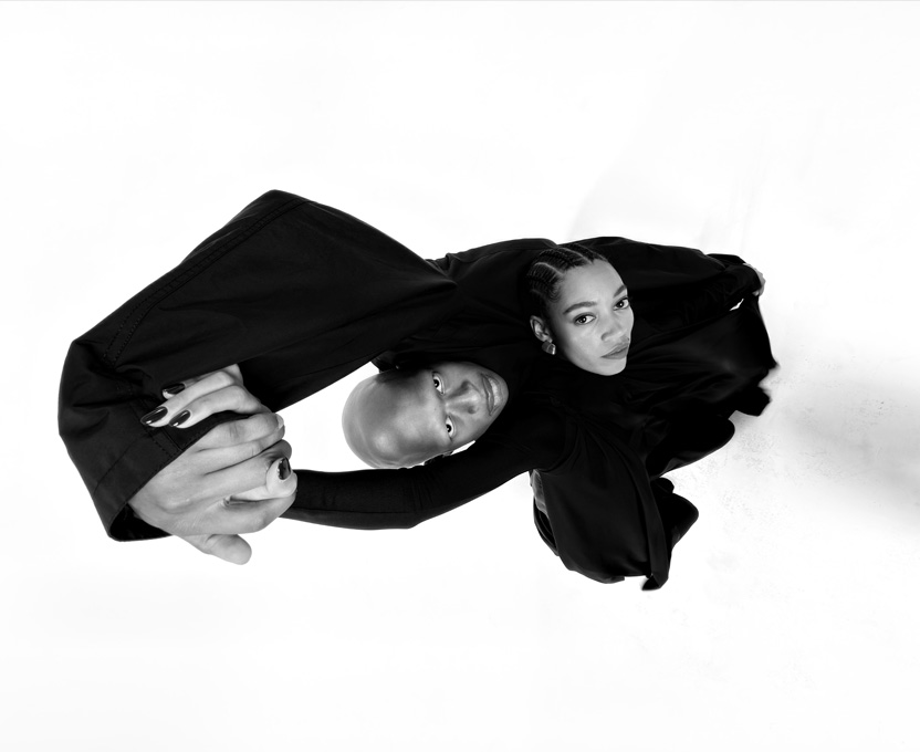 Et vidvinkelbillede i sort/hvid af to personer. Billedet demonstrerer mulighederne med ultravidvinkelkameraet i iPhone 17 Pro