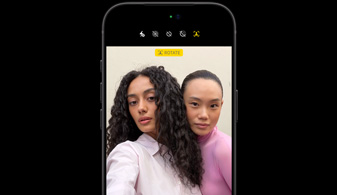 iPhone 18 Pro in Black, front-facing, showcasing two people with face tracking feature, demonstrates the Center stage front camera feature