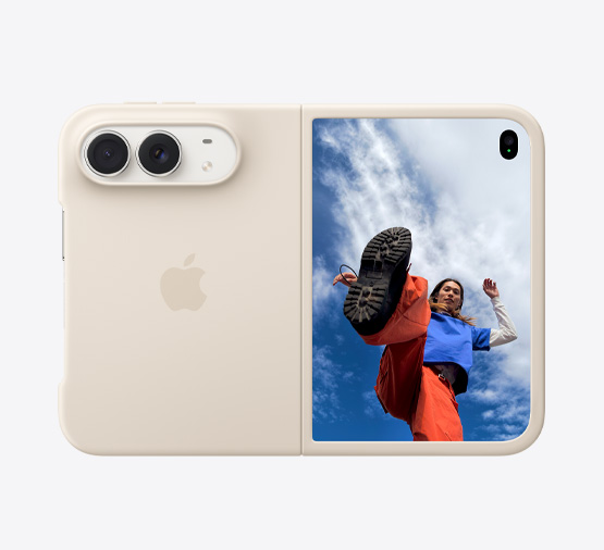 iPhone Duo, Star White color in Sand Silicone Case, landscape orientation, fully opened horizontally, Dual Fusion cameras on the top left, case covers the back exterior and outer edge of the front display, right side features the outer display with an image of a person standing under a cloud-filled blue sky