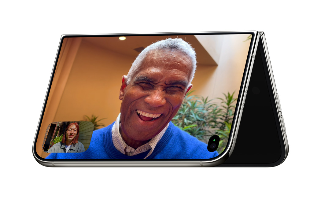 iPhone Duo propped up in an inverted V-shape resting on its edges with its screen facing outward on the Standby mode with FaceTime app