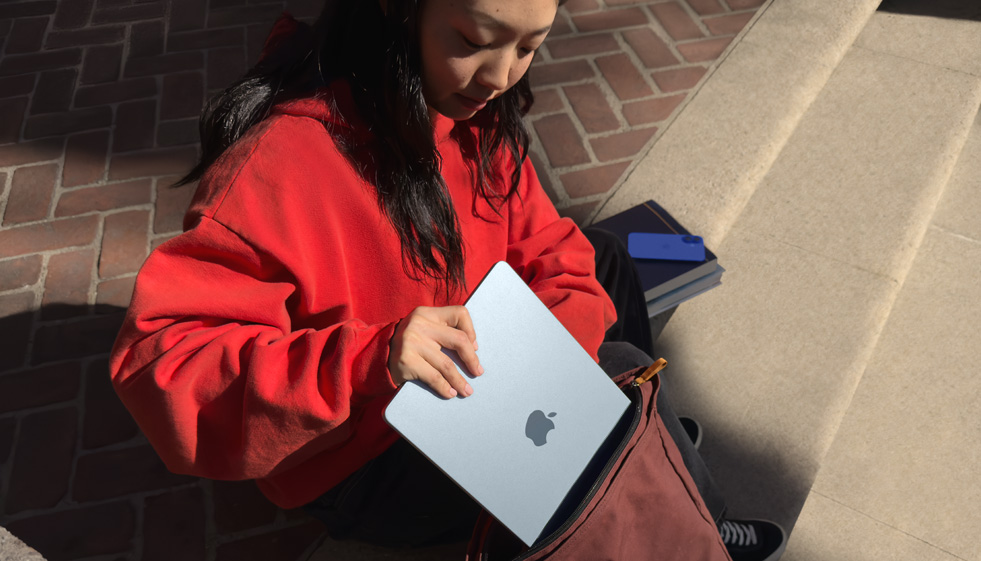 Une étudiante range un MacBook Air dans son sac