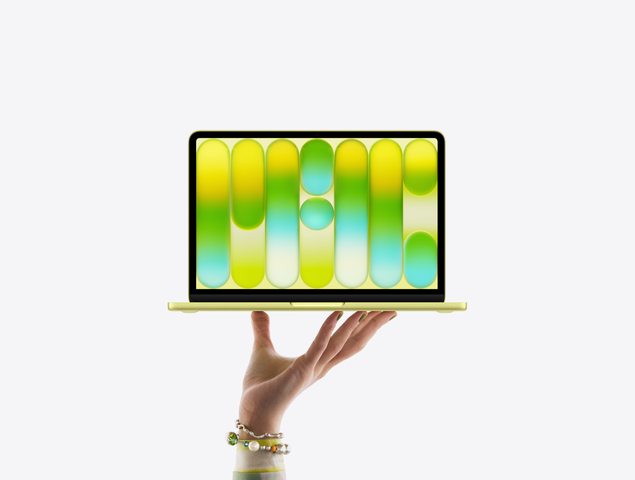 MacBook Neo in citrus color, balanced on fingertips of open hand, screen displaying colorful abstract pattern