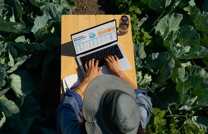 Eine Person nutzt im Freien ein MacBook Pro mit dem Display mit Nanotextur-Option und zeigt, wie Blendeffekte reduziert werden