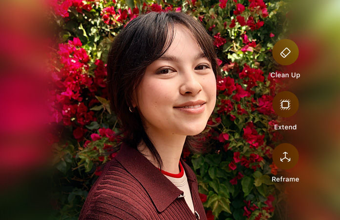 Foto de una persona sonriente de cabello castaño oscuro, vistiendo un suéter café, rodeada de flores rojas, demostración de edición de fotos con IA con las opciones Borrador, Ampliar y Reencuadrar en la foto